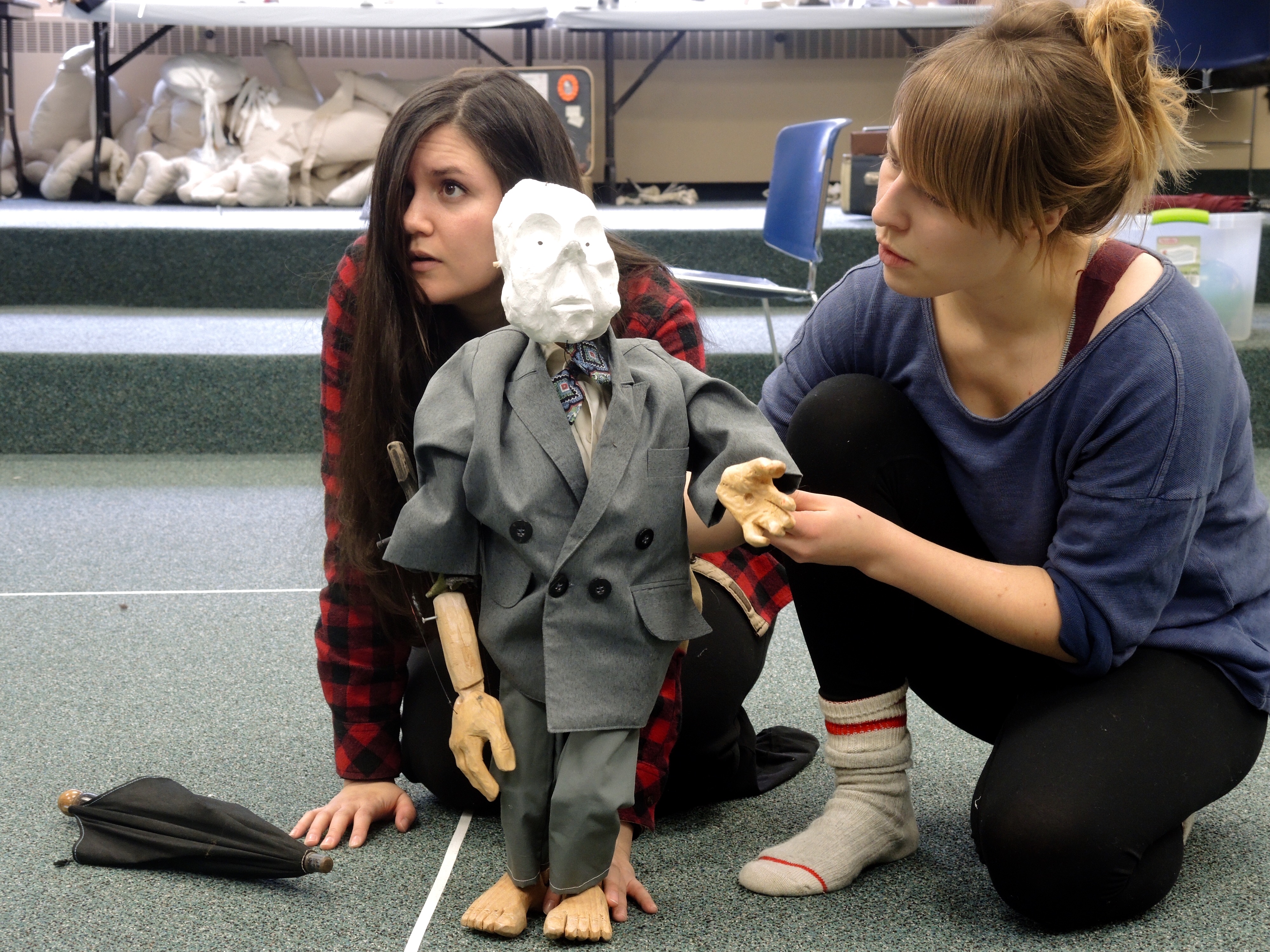 White faced puppet with two pupeteers