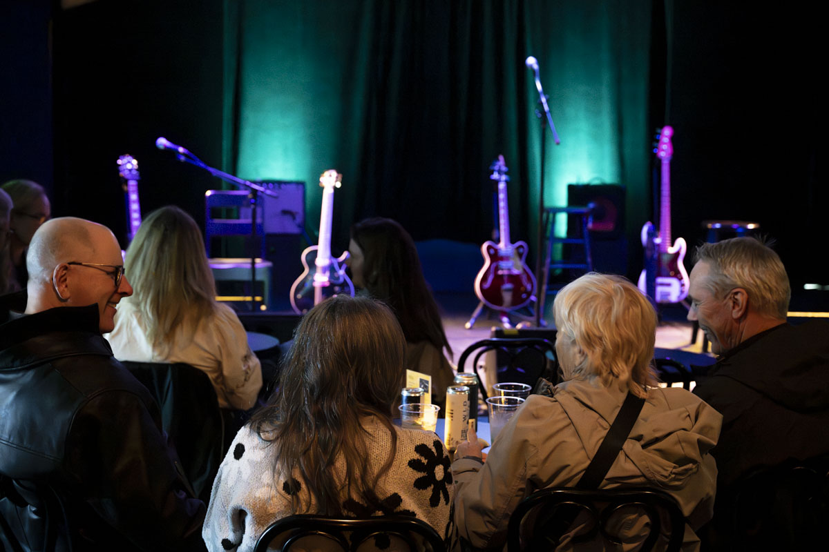 4 people seating in front of a stage in dim light 