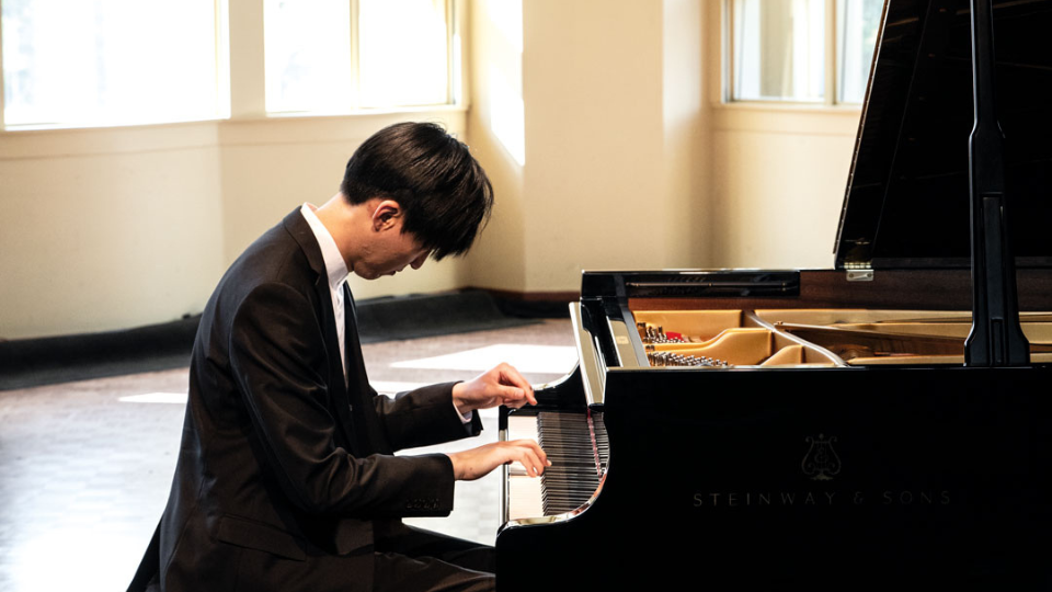 man pianist playing on a grand piano in a bright room