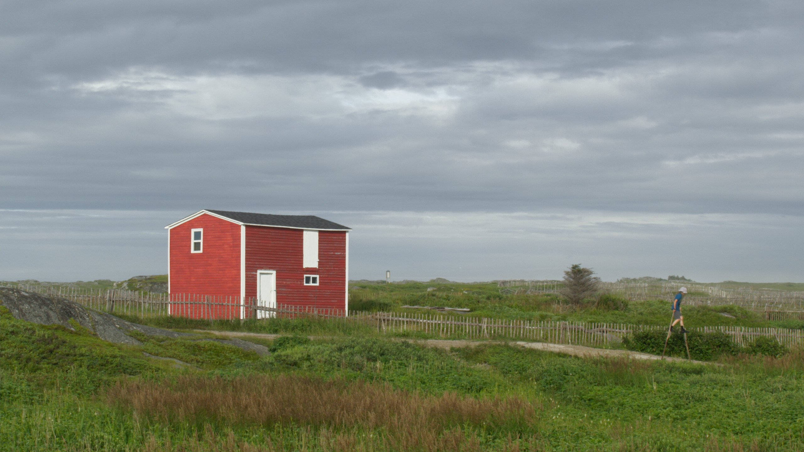 Child walking on stilts and a red building
