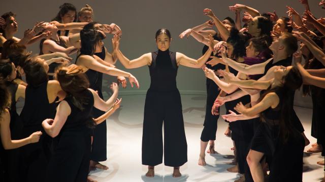 A group of dancers dressed in black are performing on a stage
