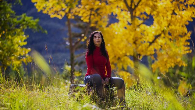 Artist Carmen Aguirre poses in a colourful forest in the fall. 