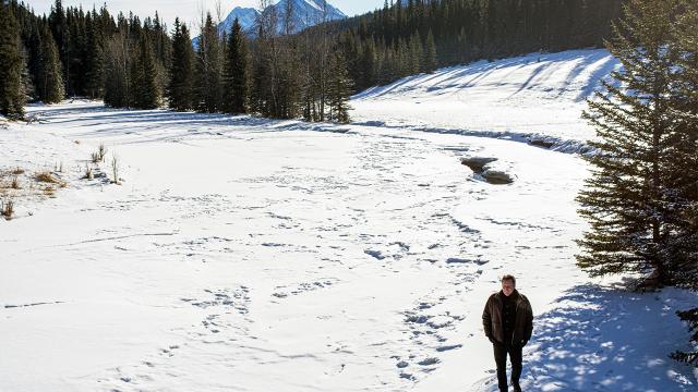 Jean Grand-Maître walks along a snow covered river. 