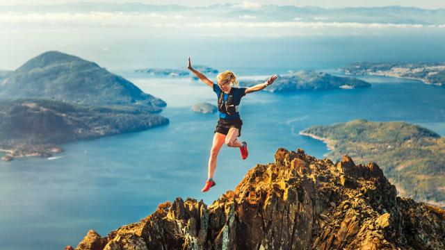 A female athlete is leaping down the mountain ridge.