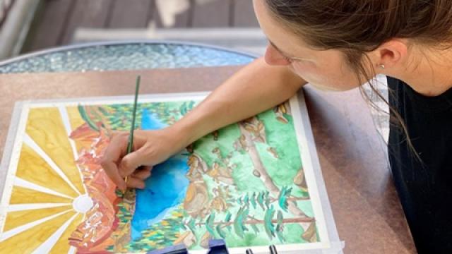 Artist Bryn Merrell creates a colorful watercolor piece with mountains and lakes.