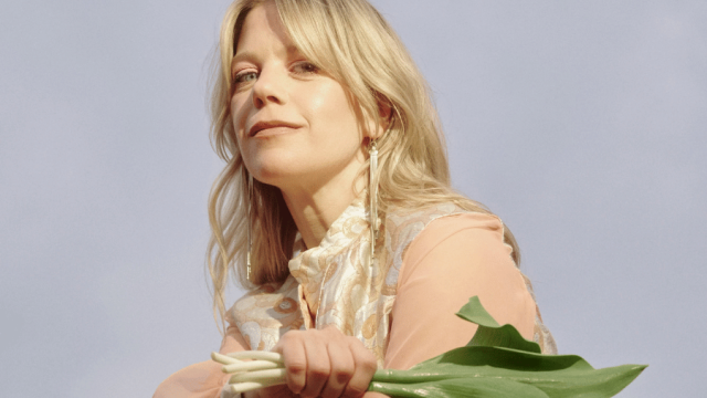 Portrait of Basia Bulat wearing a soft dress and holding flowers 