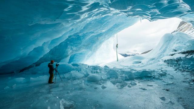 Large ice cave with cameraman filming an aerial performer 
