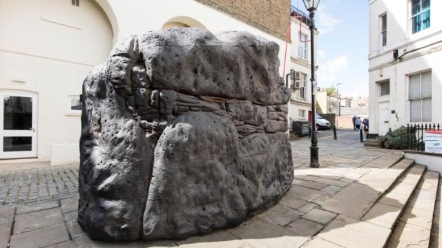 A semi-natural looking stone sits in the centre of a public square.