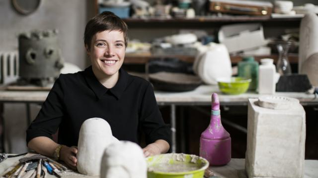 Emma Hart in a studio with a potential sculpture of clay in her hands.