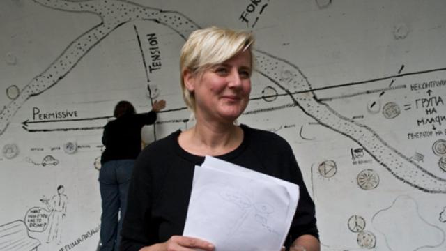 Jeanne van Heeswijk standing in front of an artistically styled map.