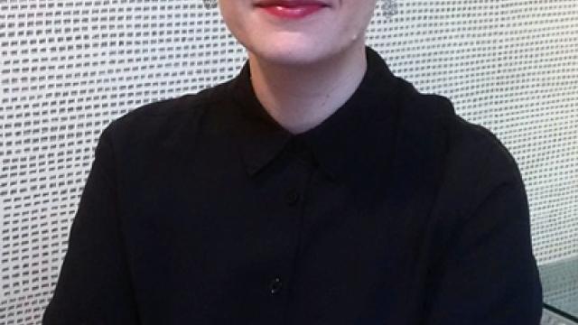 Artist Nicole Burisch stands with her arms crossed looking at the camera.