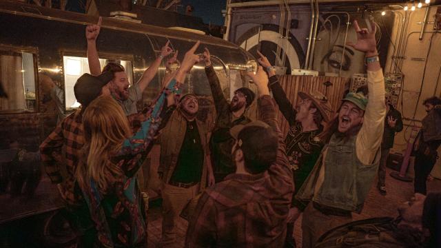 A group of men cheer in their backyard