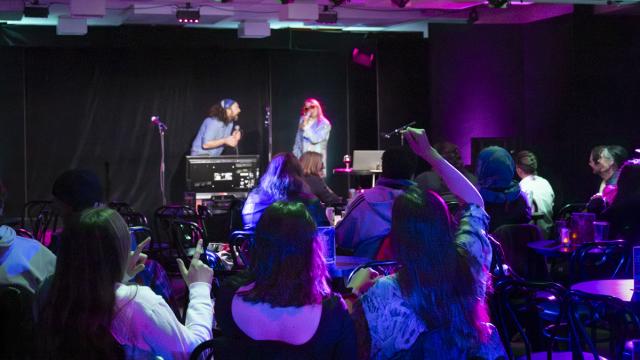 Live karaoke on stage in an intimate dime lighted setting and cheering crowed 