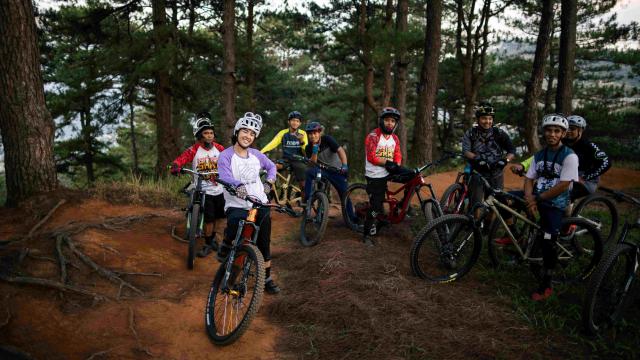 Group of young people posing on their bikes in a forest trail