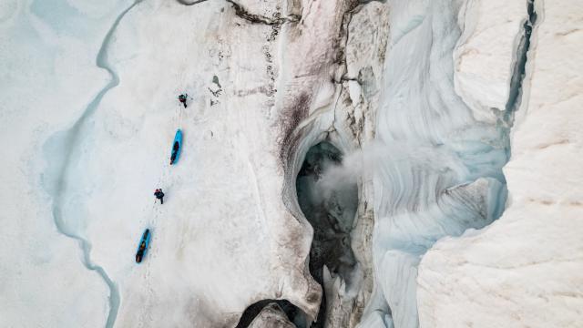 Two people pulling kayaks on a glacier 