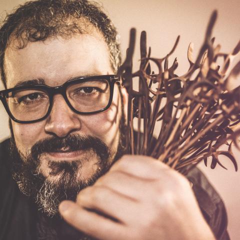 Man with dark black glasses holding flowers close to face