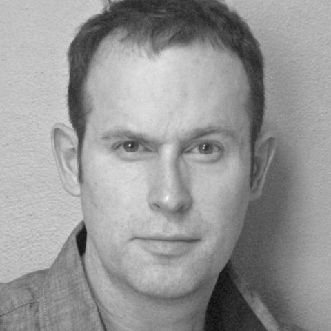 Chris, with short cropped hair, stares directly at camera with slight smile