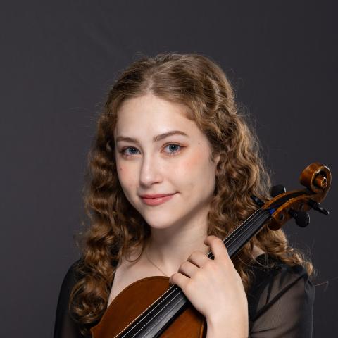 Woman holding violin and smiling at camera