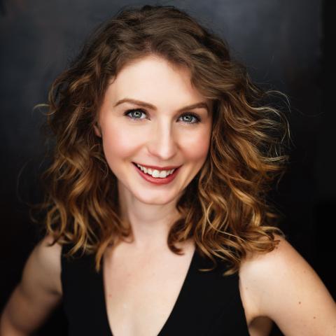 Woman standing with hands on hips and smiling directly at camera