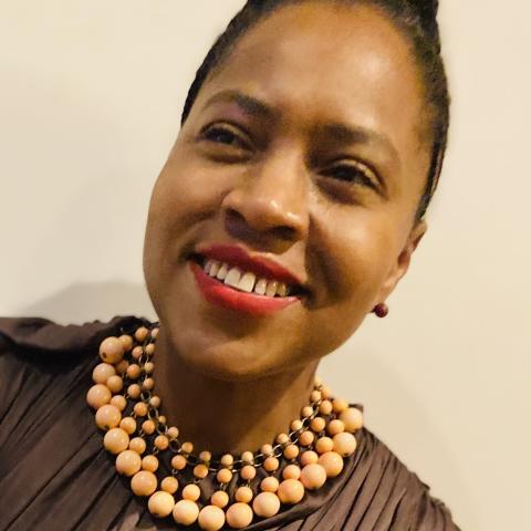 Woman smiling and looking just off camera wearing a statement bead necklace