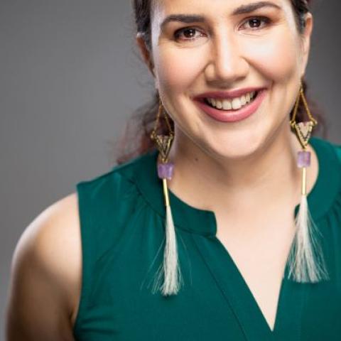 Brunette woman in a green sleeveless top smiles at the camera