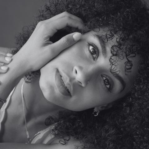 Black and white photo of woman with hand on side of face and head tilted to side