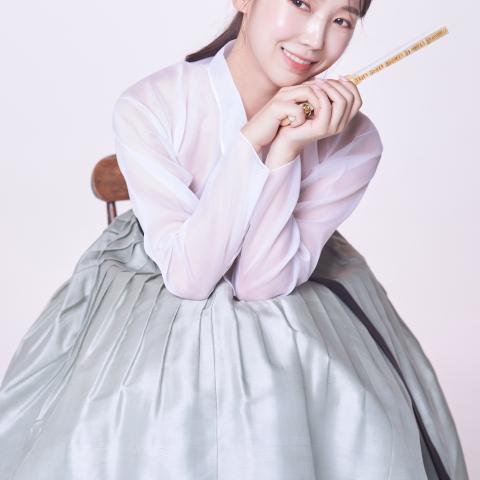 Person in purple gown holding yellow object smiling 