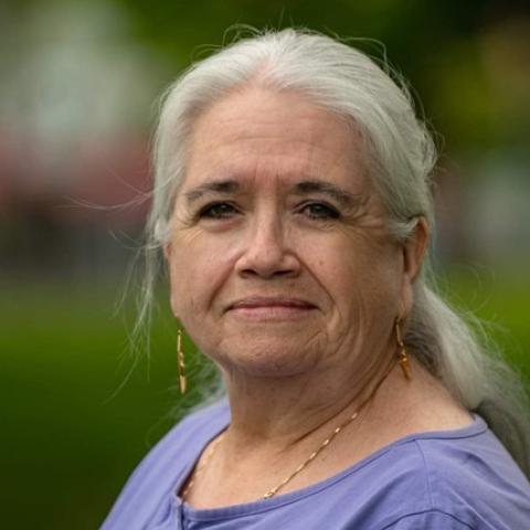 Writer Michelle Good stands outside against a blurred green background