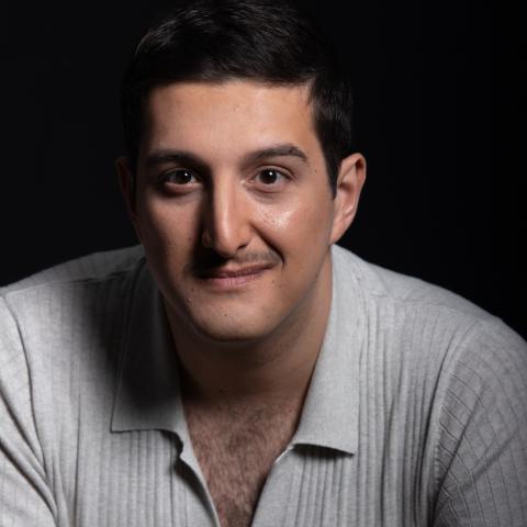 Man sitting leaning close to the camera with slight smile