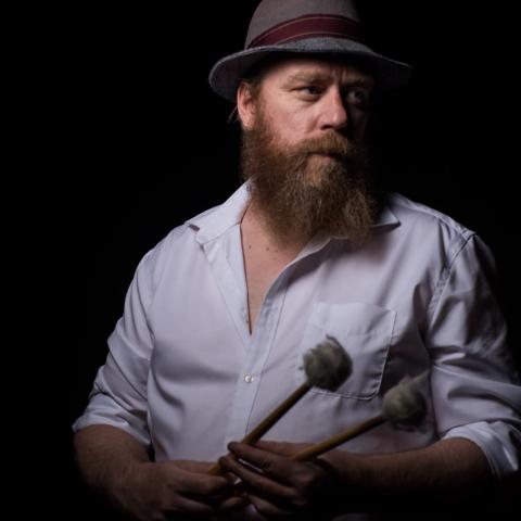 Person wearing hat and wearing a button up shirt looking off to the side