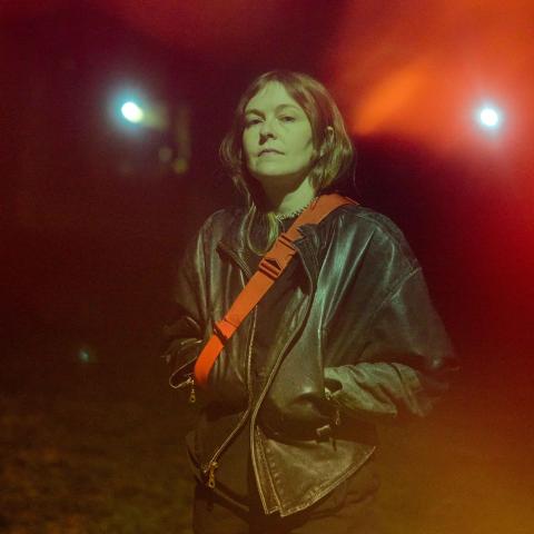 Woman in leather jacket standing in front of lights at night
