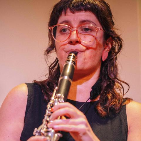 Woman playing clarinet and looking off centre