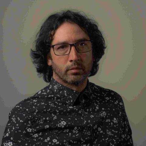 Headshot of man wearing glasses and floral button up shirt