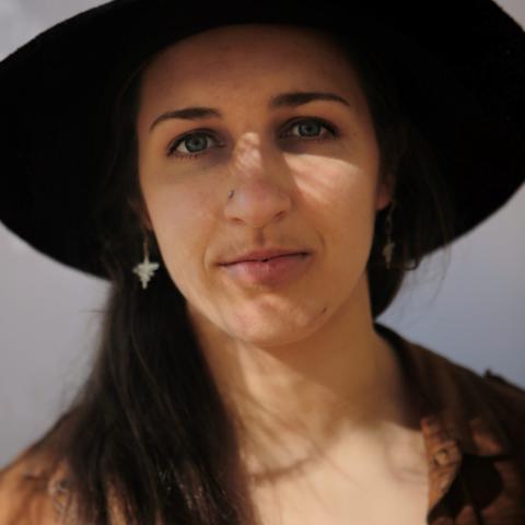 Sophie wearing a large black western style hat making direct eye contact with the camera