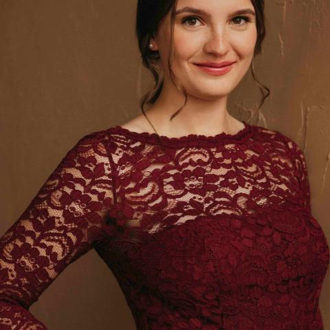 Woman in a burgundy formal dress smiling directly at the camera