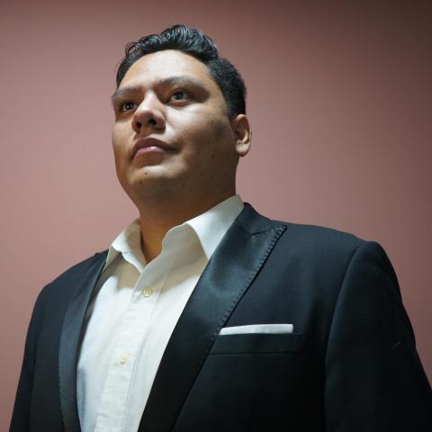 Dramatic shot from below of a man in a dress jacket and crisp white shirt smiling off camera