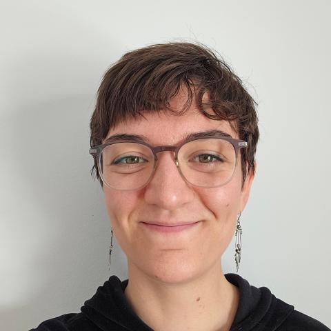 Close up shot of short haired woman wearing glasses and smiling at the camera