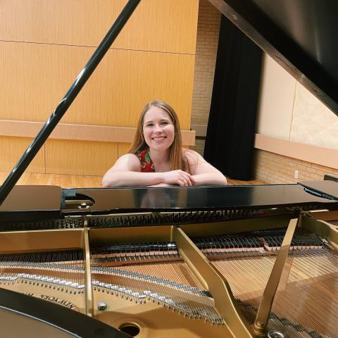Woman smiling at the camera while sitting behind the piano