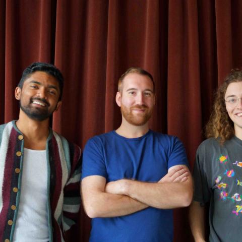 Members of Interstitial Gestures standing in front of a red curtain