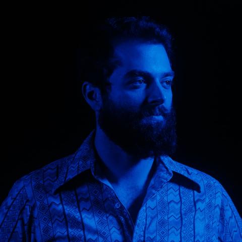A darkly lit close up on Martin's face with a blue coloured light. 