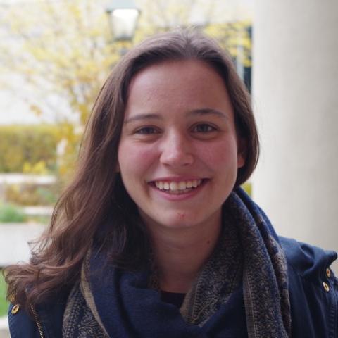 A close up of Claire smiling outdoors with a blurry streetlamp and tree behind. 