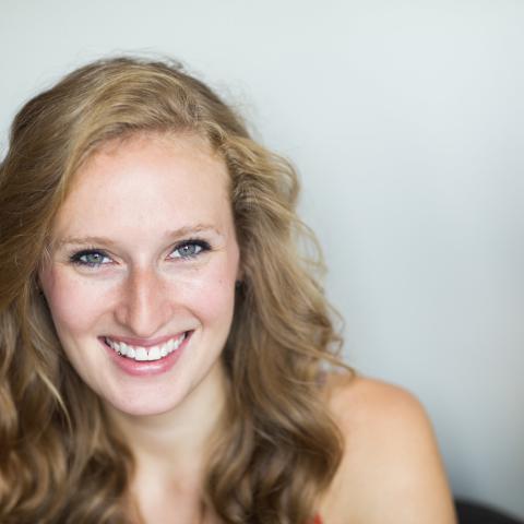 A close up photo of Kathleen. She in front of a blurry white background. She is smiling.