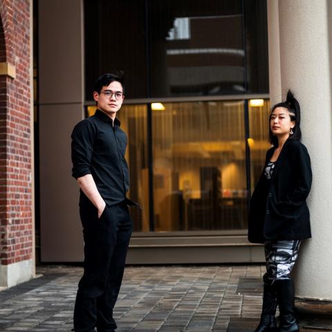 Members of In Case of Fire Play the Lute to the Cow standing outside a building. One member leaning against a pillar