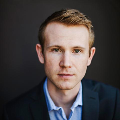Headshot of person in blue staring into camera 