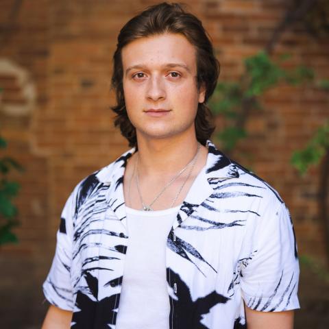 Person standing in front of brick wall in a black and white shirt