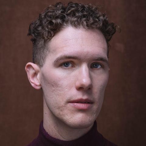 Headshot with burgundy coloured background and shirt 