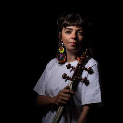 Person looking into the camera holding a string instrument