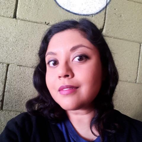 Woman with dark hair and wearing a blue t-shirt and cardigan.