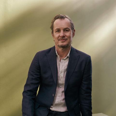 Man with blazer on looking directly at camera 