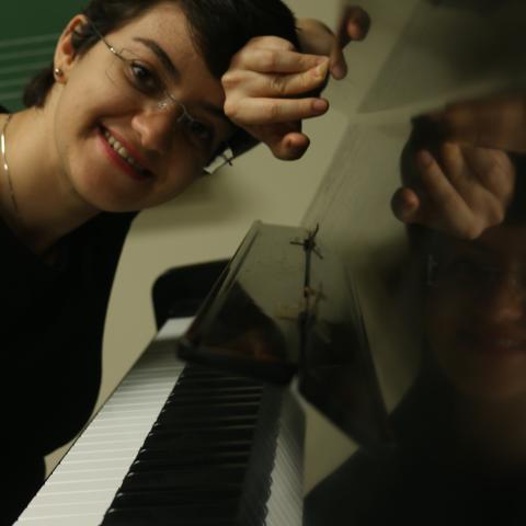 Person leaning on piano looking a the camera smilling